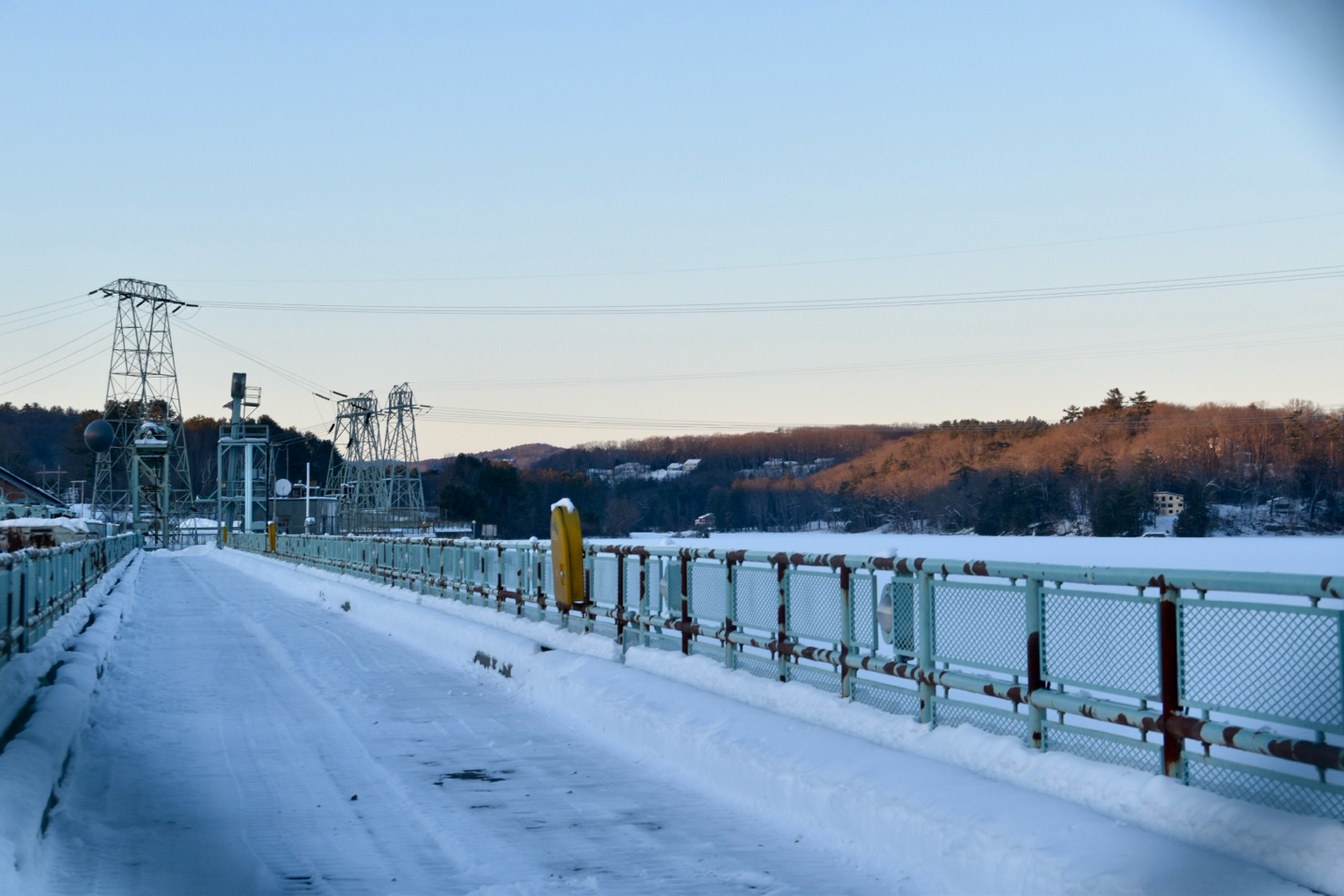 A snowy pedestrian walkway on a bridge at dusk